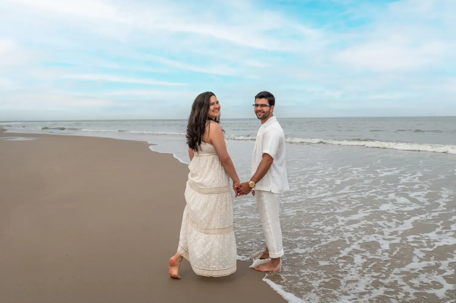 Casal de mãos dadas caminhando à beira-mar, no litoral de Den Haag