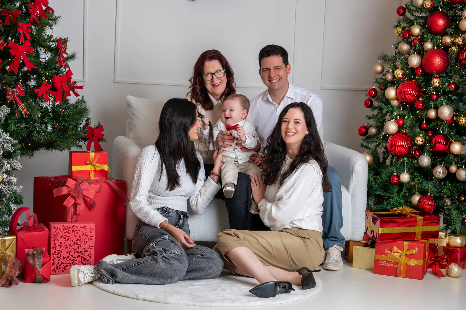 Família reunida na sala decorada de Natal com o bebê no colo